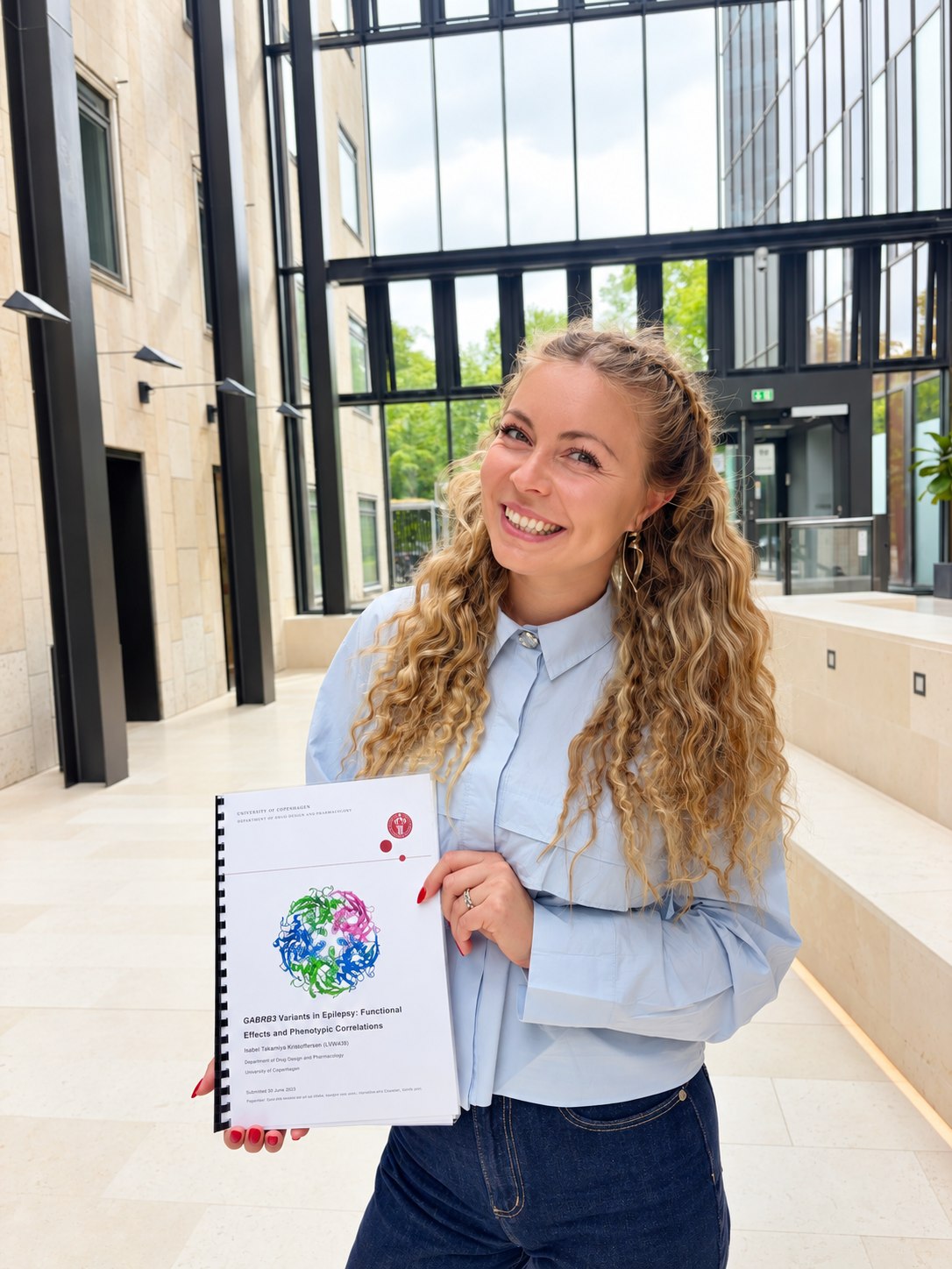 Isabel Takamiya Kristoffersen holding her MSc thesis in Pharmacy, University of Copenhagen