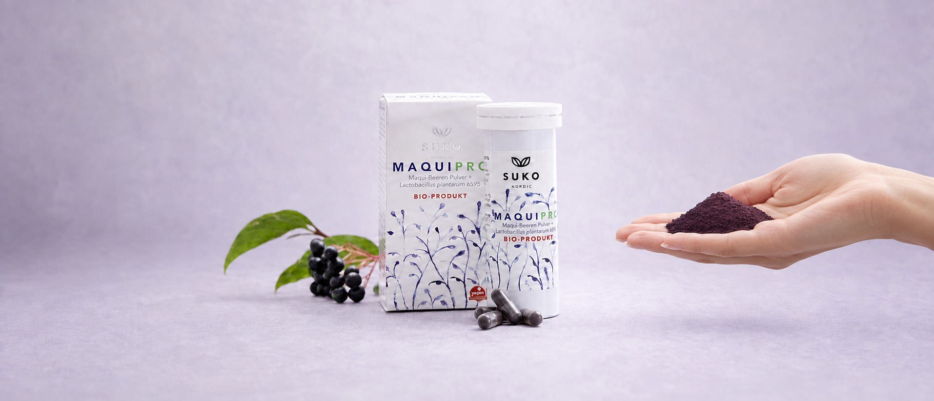 MaquiPro® maqui berry and probiotic product box, tube and capsules with fresh maqui berries and a hand holding maqui powder