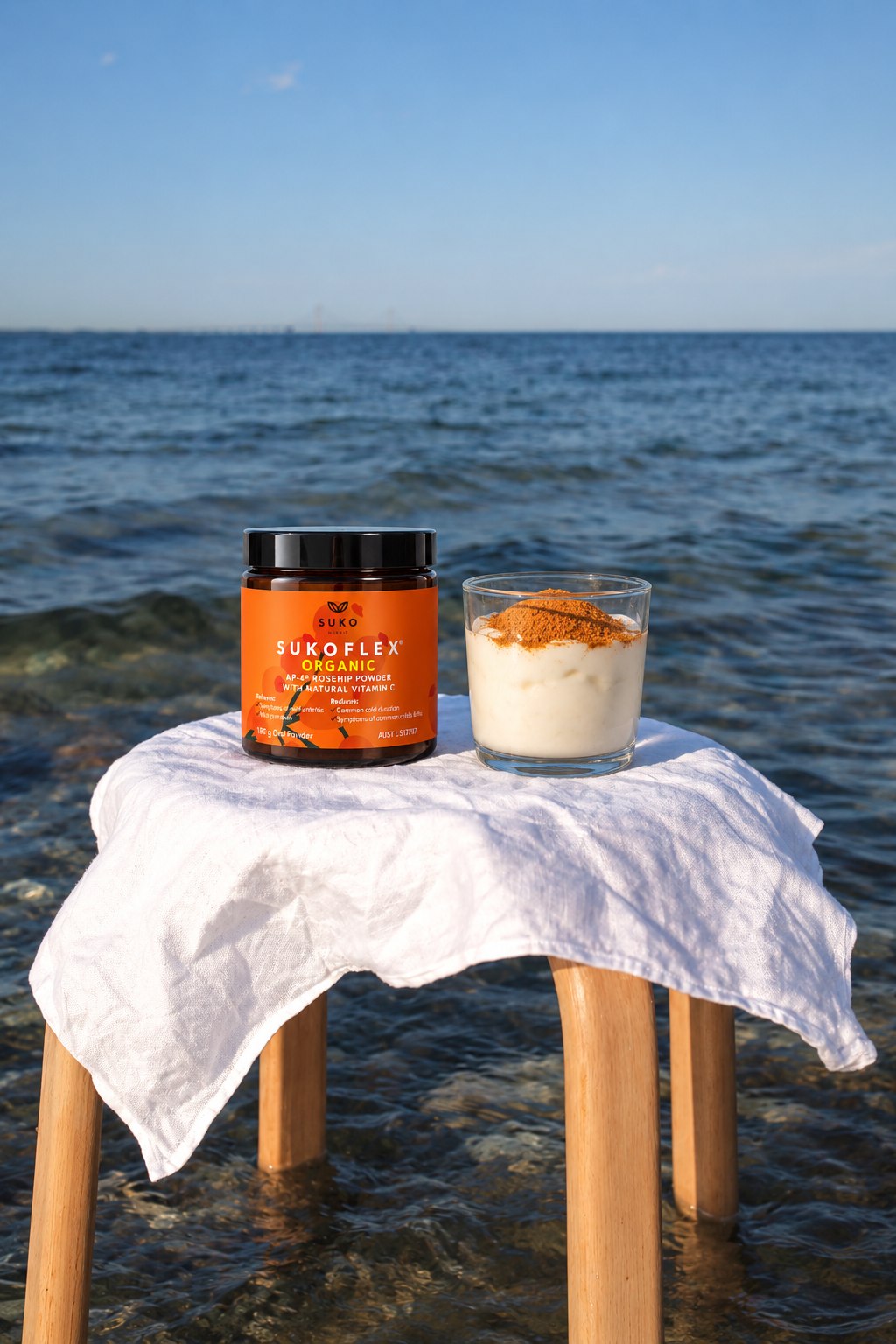 SUKOFLEX Organic rosehip powder jar beside a smoothie bowl on a table by the sea