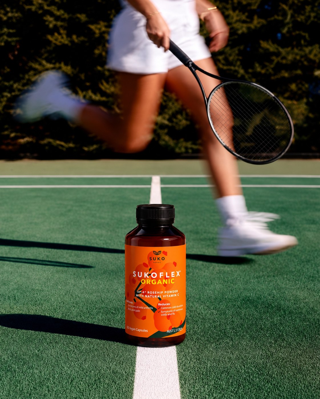 SUKOFLEX Organic capsule bottle on a tennis court with a player in motion behind it